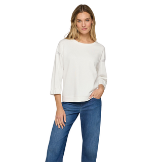 Woman wearing a white sweater and blue jeans on a white background