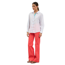 Load image into Gallery viewer, Woman wearing a white button-up shirt and coral pants on a white background

