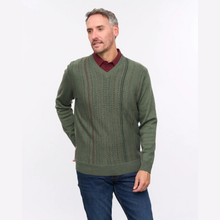 Load image into Gallery viewer, A man wearing an olive green knit sweater with vertical textured stripes, layered over a burgundy collared shirt and blue jeans, standing against a plain white studio background.
