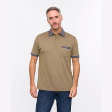 Load image into Gallery viewer, A man wearing a short-sleeve polo shirt in a heathered khaki-brown color with dark gray accents on the collar, sleeve cuffs, and chest pocket, paired with blue jeans, against a plain white studio background.
