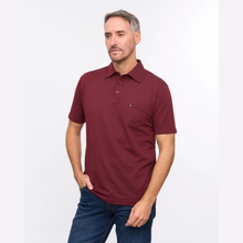 Load image into Gallery viewer, A man wearing a short-sleeve polo shirt in burgundy with a small embroidered logo on the chest pocket, paired with blue jeans, photographed against a plain white studio background.
