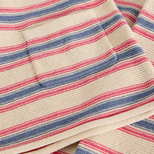 Load image into Gallery viewer, Close-up of a woven textile with horizontal stripes in cream, dusty blue, and coral pink, showing a small stitched pocket on the left side.
