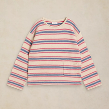 Load image into Gallery viewer, A long-sleeve knit sweater with horizontal stripes in pink, blue, and red on a cream base, featuring a small front patch pocket, laid flat on a textured beige background.
