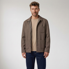 Load image into Gallery viewer, A man wearing a brown wool-blend utility jacket over a beige t-shirt and dark blue jeans, standing against a light gray studio background.
