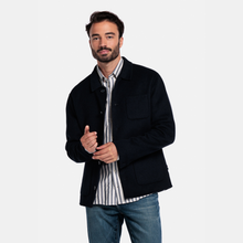 Load image into Gallery viewer, Man wearing a navy jacket over a striped shirt with a plain background
