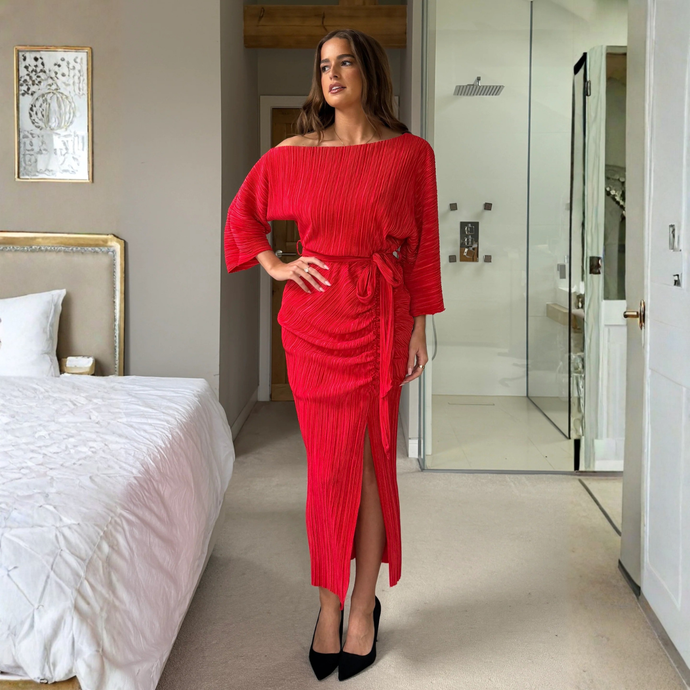 Woman in a red dress standing in a modern bedroom.
