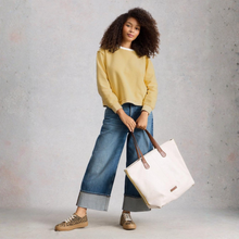 Load image into Gallery viewer, Woman holding a white tote bag against a gray background
