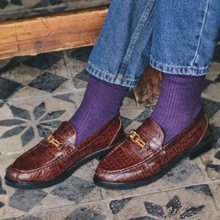 Load image into Gallery viewer, Brown loafers with gold accents worn with purple socks on a patterned floor.
