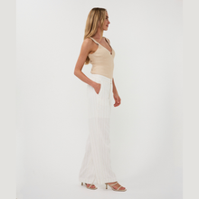 Load image into Gallery viewer, Woman wearing a beige top and white pants on a plain background
