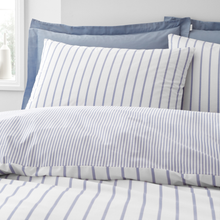 Load image into Gallery viewer, Striped bedding with blue and white pattern on a bed in a room.
