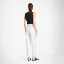 Load image into Gallery viewer, Woman wearing a black sleeveless top and white pants on a white background
