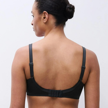 Load image into Gallery viewer, A woman shown from the back wearing a black bra with wide shoulder straps and a wide back band, photographed against a plain light gray studio background.
