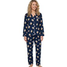 Load image into Gallery viewer, A woman modeling a navy blue pajama set with a beige and white floral pattern, consisting of a long-sleeve button-up top and matching pants, against a plain white background.
