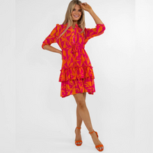 Load image into Gallery viewer, female model with hand on hair and waist smiling in pink and orange dress
