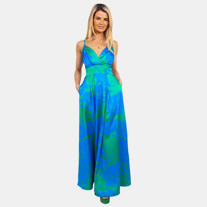 Female model standing in blue and green dress with hands in pockets.