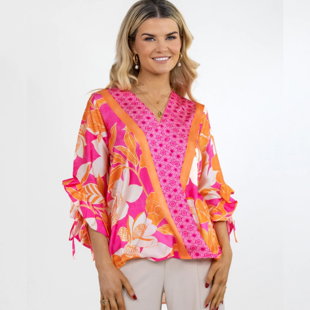 Female model smiling wearing pink and orange floral top