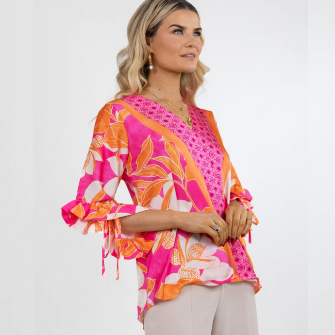 Female model wearing pink and orange floral top looking to the right 