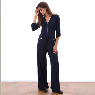 Woman wearing a navy blue jumpsuit standing on a wooden floor.