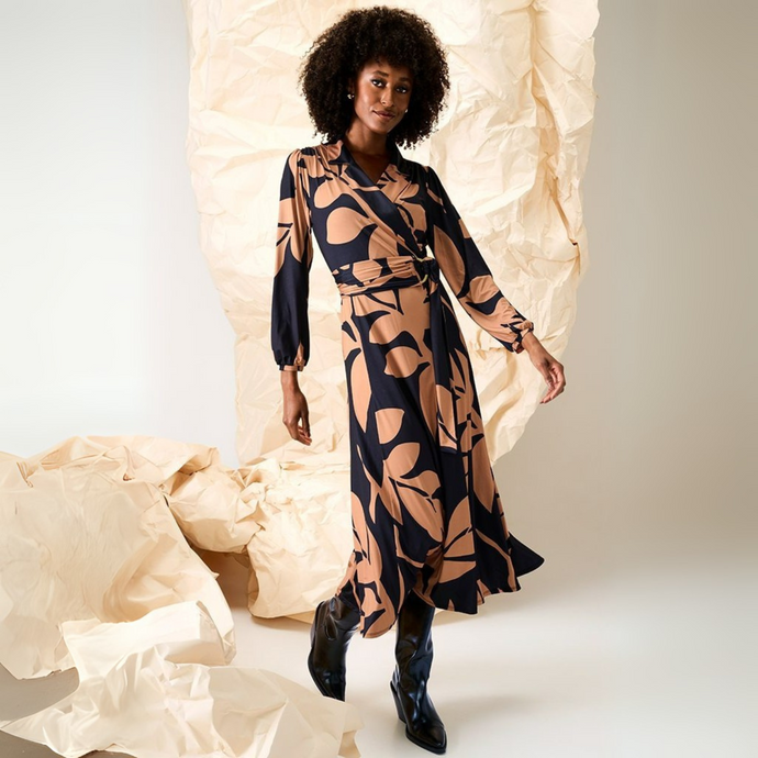 Woman wearing a patterned dress standing against a textured beige background