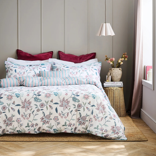 Bedroom with floral bedding and decorative pillows on a bed.