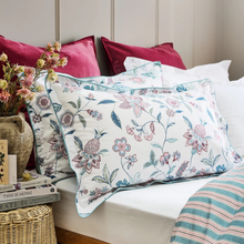Load image into Gallery viewer, Floral patterned pillow on a bed with decorative pillows and a vase of flowers.
