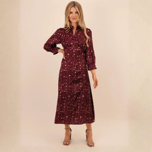 Load image into Gallery viewer, A woman modeling a long-sleeved midi dress in burgundy with a small pink and white polka dot pattern, standing against a plain beige studio background.
