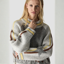 Load image into Gallery viewer, A woman wearing a fuzzy knit sweater with a high mock neck, featuring a heather gray body with yellow and brown geometric stripe patterns.
