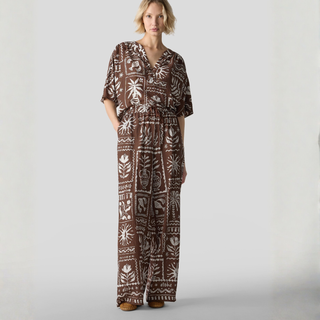 Woman wearing a brown patterned jumpsuit on a white background