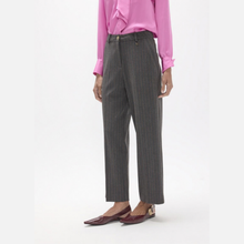 Load image into Gallery viewer, A model wearing dark gray pinstripe trousers, a bright pink blouse, and burgundy pointed flats, shown from the waist down against a plain white studio background.
