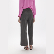 Load image into Gallery viewer, A model from the back wearing high-waisted, wide-leg charcoal gray trousers with thin vertical pinstripes, paired with a pink blouse and brown sandals, against a plain white studio background.
