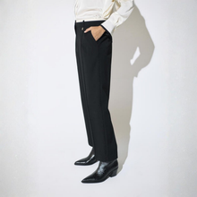 Load image into Gallery viewer, A person wearing black wide-leg trousers, a cream satin shirt, and black pointed-toe ankle boots, standing against a white wall with a strong shadow.
