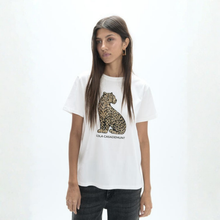 Load image into Gallery viewer, A woman modeling a white short-sleeve graphic T-shirt featuring a large leopard print on the front with the text 'OLA CASADEMUNT' underneath, paired with dark jeans against a plain white studio background.
