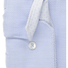 Load image into Gallery viewer, Close-up of a light blue textured dress shirt with a matching patterned necktie and a white button.
