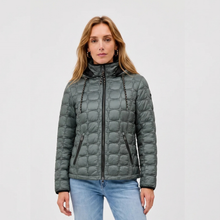 Load image into Gallery viewer, A woman wearing a dark gray quilted puffer jacket with black zipper details and drawstrings, paired with light blue jeans, against a plain light gray background.
