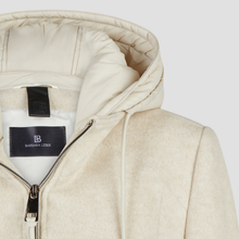 Load image into Gallery viewer, Close-up of a cream-colored hooded jacket with a black zipper and a black interior label reading Barbara Leick.
