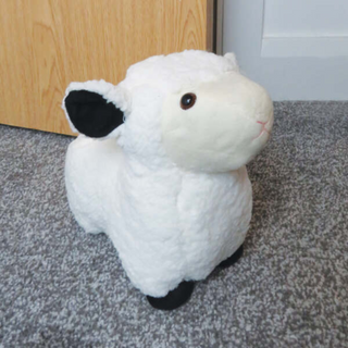 White Fluffy Sheep side view beside a door with black ear and black feet 