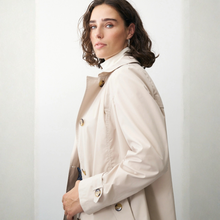 Load image into Gallery viewer, Woman wearing a beige trench coat against a plain background
