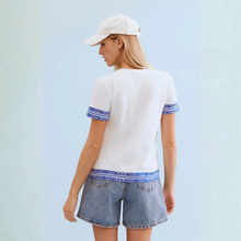 Load image into Gallery viewer, Woman in White T with Blue print and shorts on pale background 
