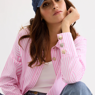Woman wearing a pink and white striped shirt with decorative buttons on a white background