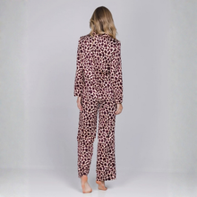 Load image into Gallery viewer, A woman viewed from behind wearing a matching long-sleeve pajama set with an allover leopard print pattern in brown and beige tones, standing against a light gray studio background.
