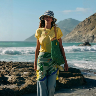 Person standing on a rocky beach with ocean and mountains in the background