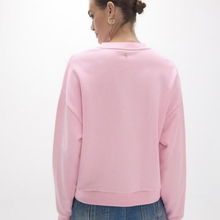Load image into Gallery viewer, A woman shown from the back wearing a light pink crewneck sweatshirt and blue jeans against a plain white background.
