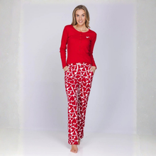 Load image into Gallery viewer, A woman modeling a two-piece pajama set consisting of a solid red long-sleeve top and red pants with a white broken-heart pattern, standing against a light gray studio background.
