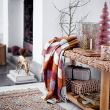 Load image into Gallery viewer, Decorative living room with a colorful blanket, small Christmas tree, and festive decor.
