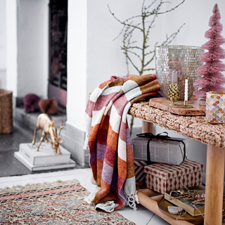 Decorative living room with a colorful blanket, small Christmas tree, and festive decor.