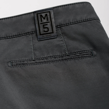 Load image into Gallery viewer, Close-up of the back waistband of dark gray trousers, showing a black woven patch with the letters 'M5' and 'ST. MARTIN'.
