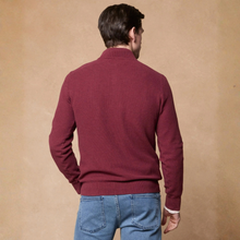 Load image into Gallery viewer, A man viewed from behind wearing a burgundy knit mock-neck sweater and blue jeans, standing against a textured tan background.
