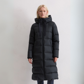 Person wearing a long black puffer coat against a plain background