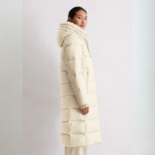 Load image into Gallery viewer, Woman wearing a long cream puffer coat on a white background
