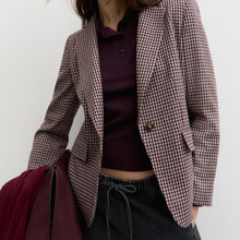 Load image into Gallery viewer, A person wearing a brown and burgundy gingham blazer over a dark plum polo shirt, paired with dark drawstring pants, against a plain off-white wall.
